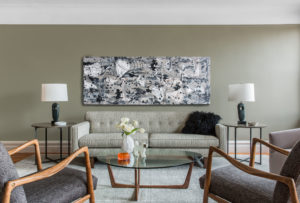 head-on photo of an apartment living room sofa with an abstract painting over it
