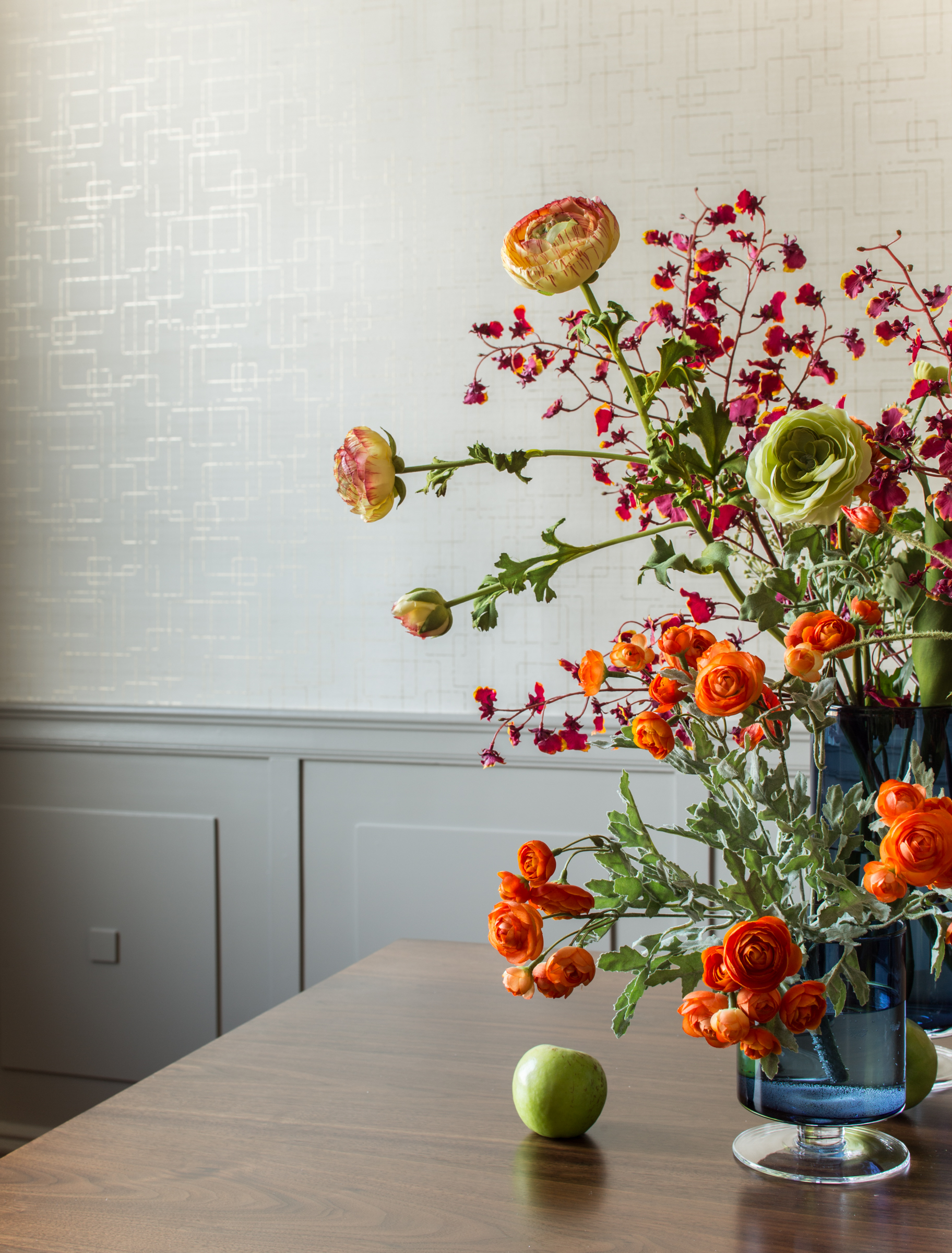 flowers in a blue vase in front of a textured painted white wall with wainscoting