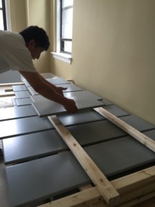 worker placing a cabinet door on a rack to dry