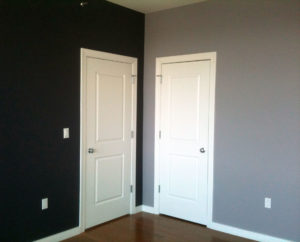two white doors in the corner of a room with a navy blue wall and a gray wall