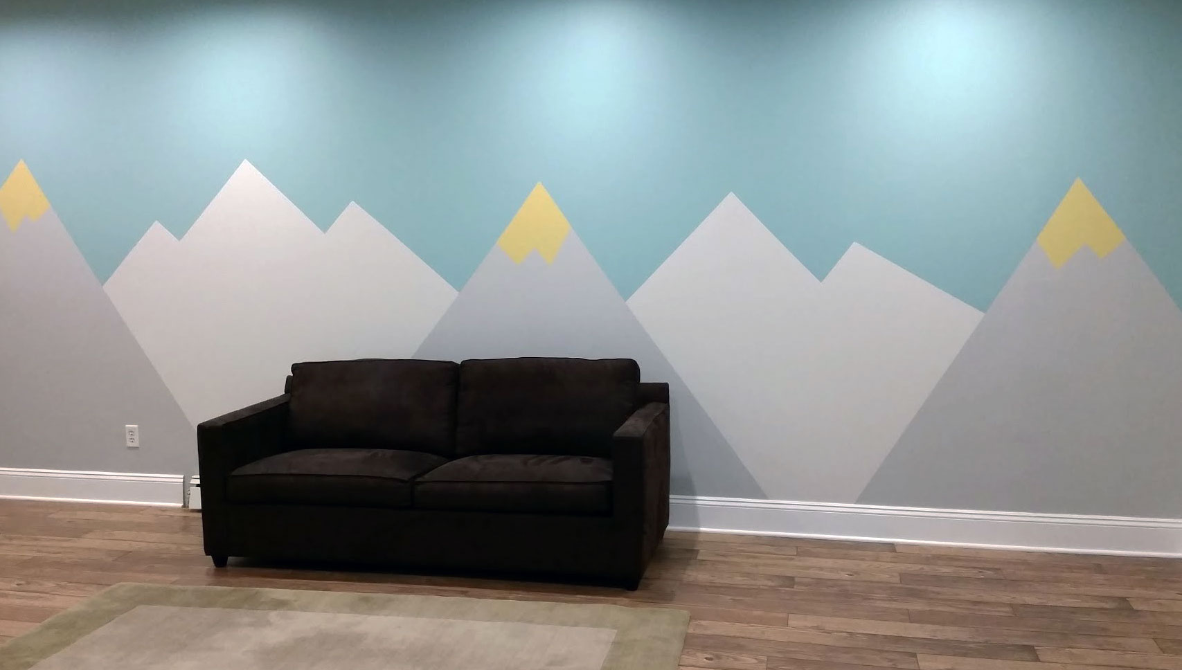 Sofa sitting against a custom painted wall of mountains