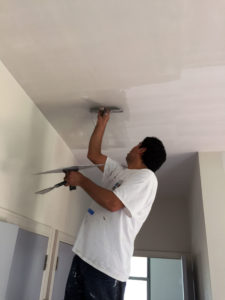 man applying drywall compound to a ceiling