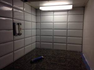 Small cubby area with electrical outlets and white subway tile