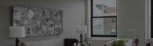 A New York City apartment living room with abstract black and white painting on the wall and windows with partial views of the Hudson River