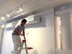 worker on a ladder painting a wall in a retail space