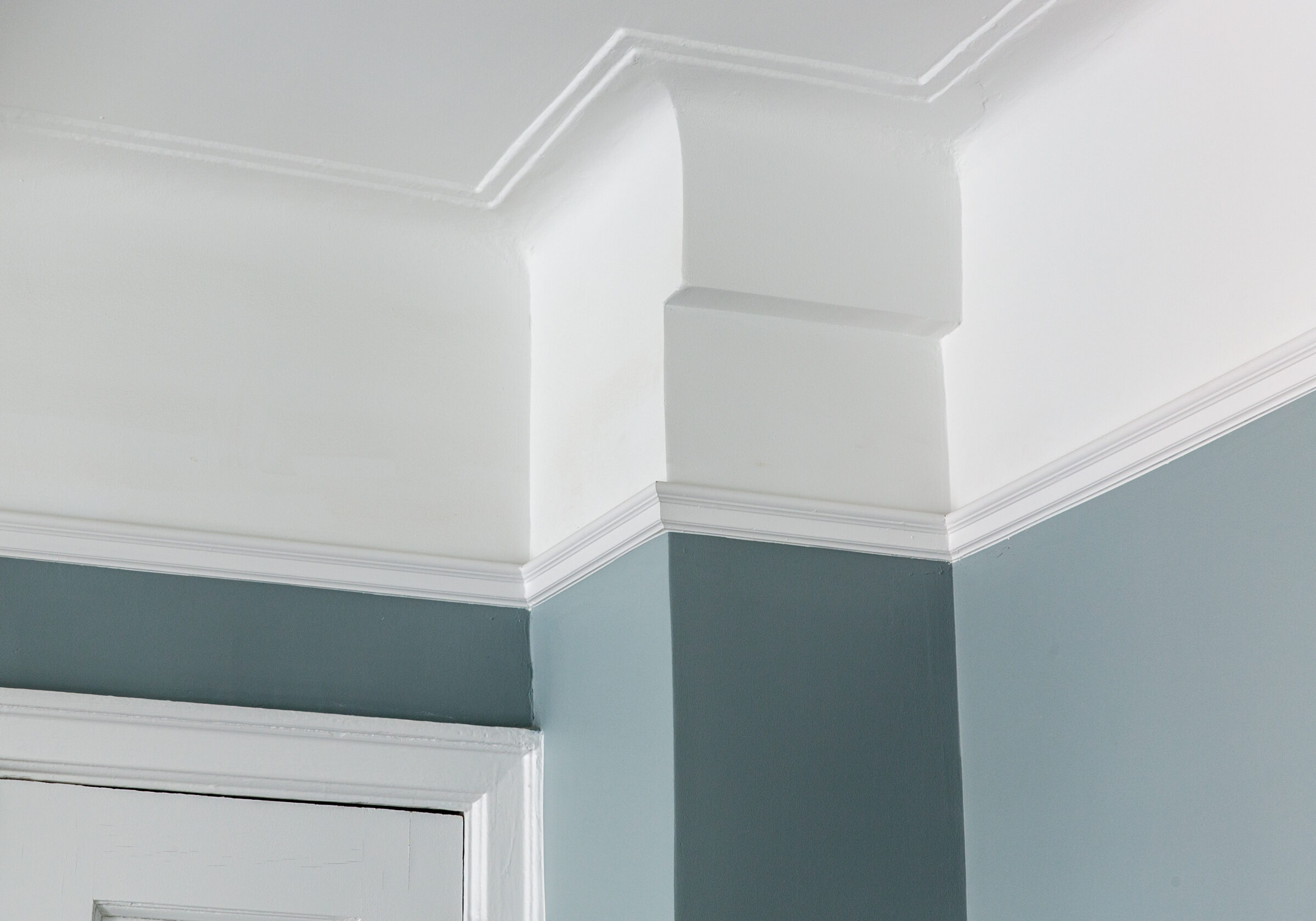 rown molding and door casing in white against a blue-grey wall