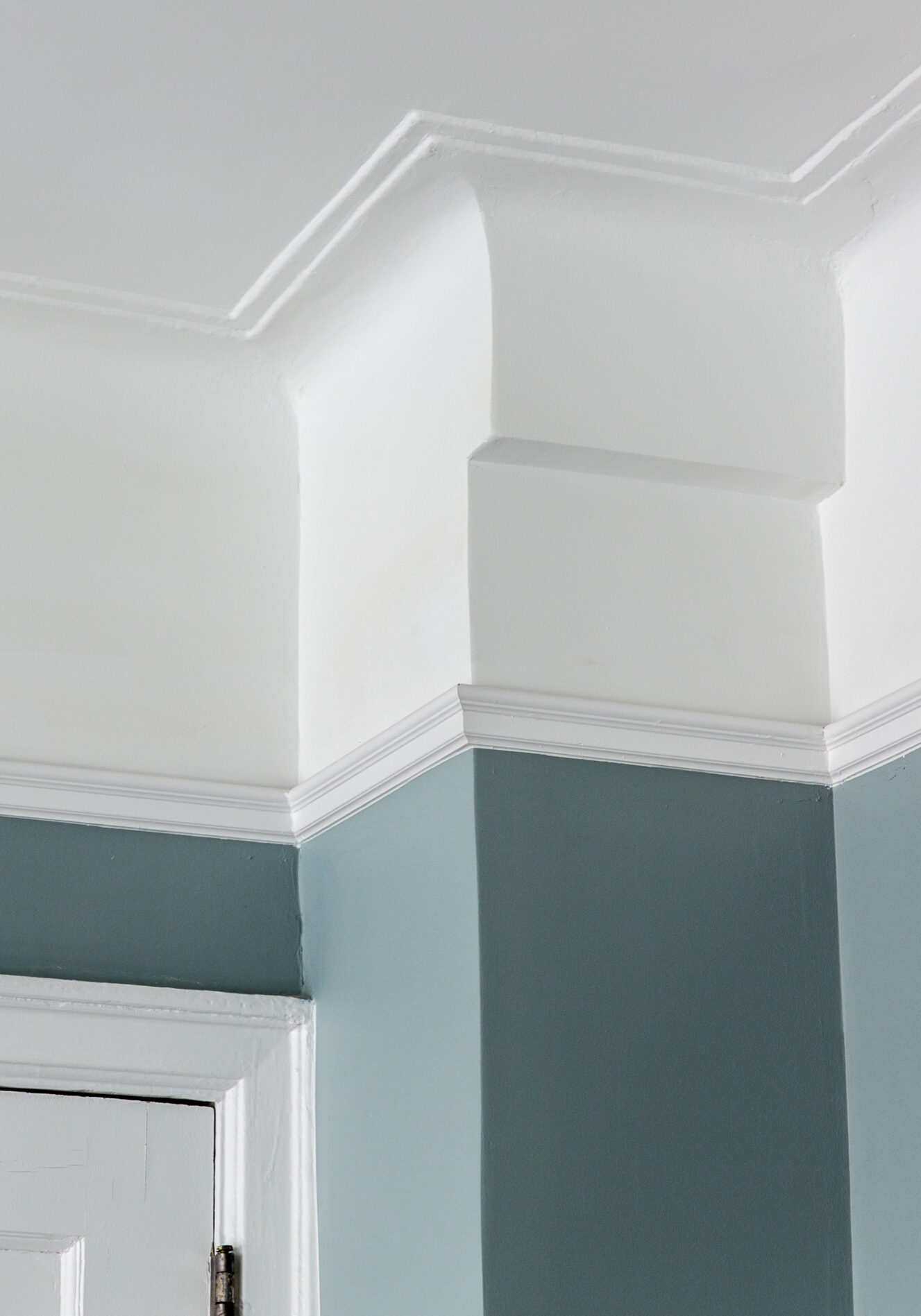 rown molding and door casing in white against a blue-grey wall