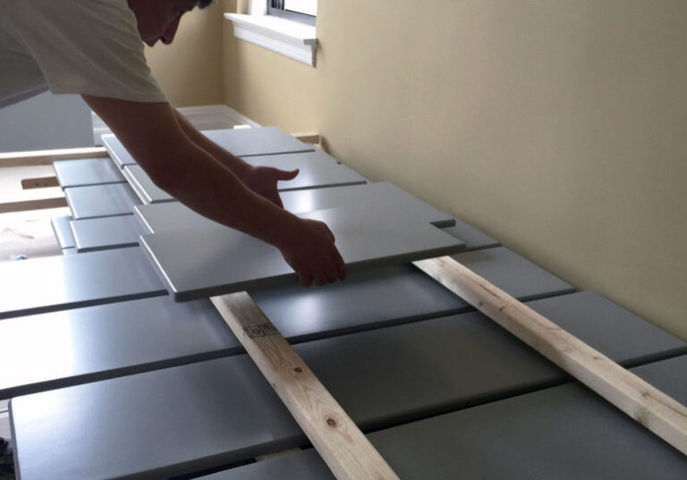 a worker putting a freshly painted cabinet door on a drying rack