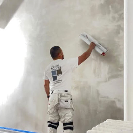 worker skim coating drywall to prepare for painting